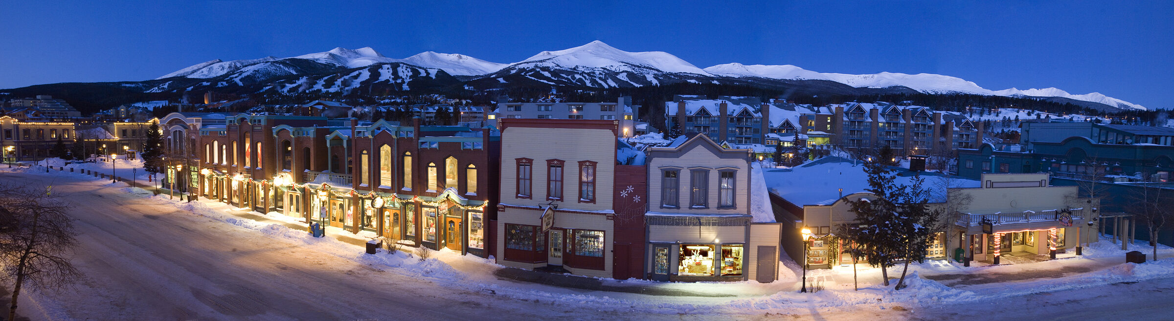 Main Street de Breckenridge iluminada de noche, con los picos nevados de la estación al fondo